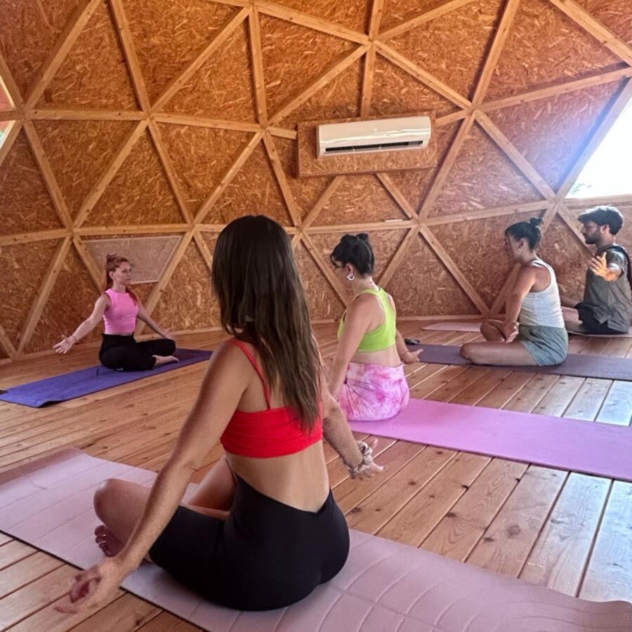 Grupo practicando yoga sentado sobre esterillas, guiado por Raquel